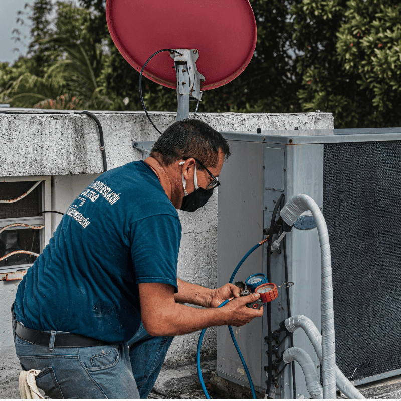 Technician inspecting rooftop HVAC unit on commercial building
